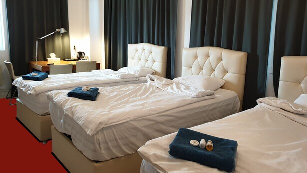 A hotel room with three beds, a desk, and a lamp. - Patrician Hotel (Trangsund)