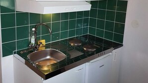A compact kitchen with a sink, stove, and white cabinets. - Patrician Hotel (Trangsund)