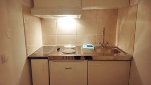 A compact kitchen with a built-in stove, a sink, and a microwave. - Patrician Hotel (Trangsund)