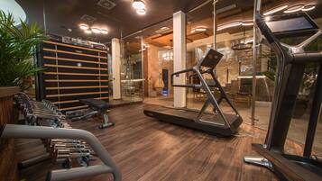 Un gimnasio moderno con equipo de ejercicio, suelo de madera y paredes de vidrio.