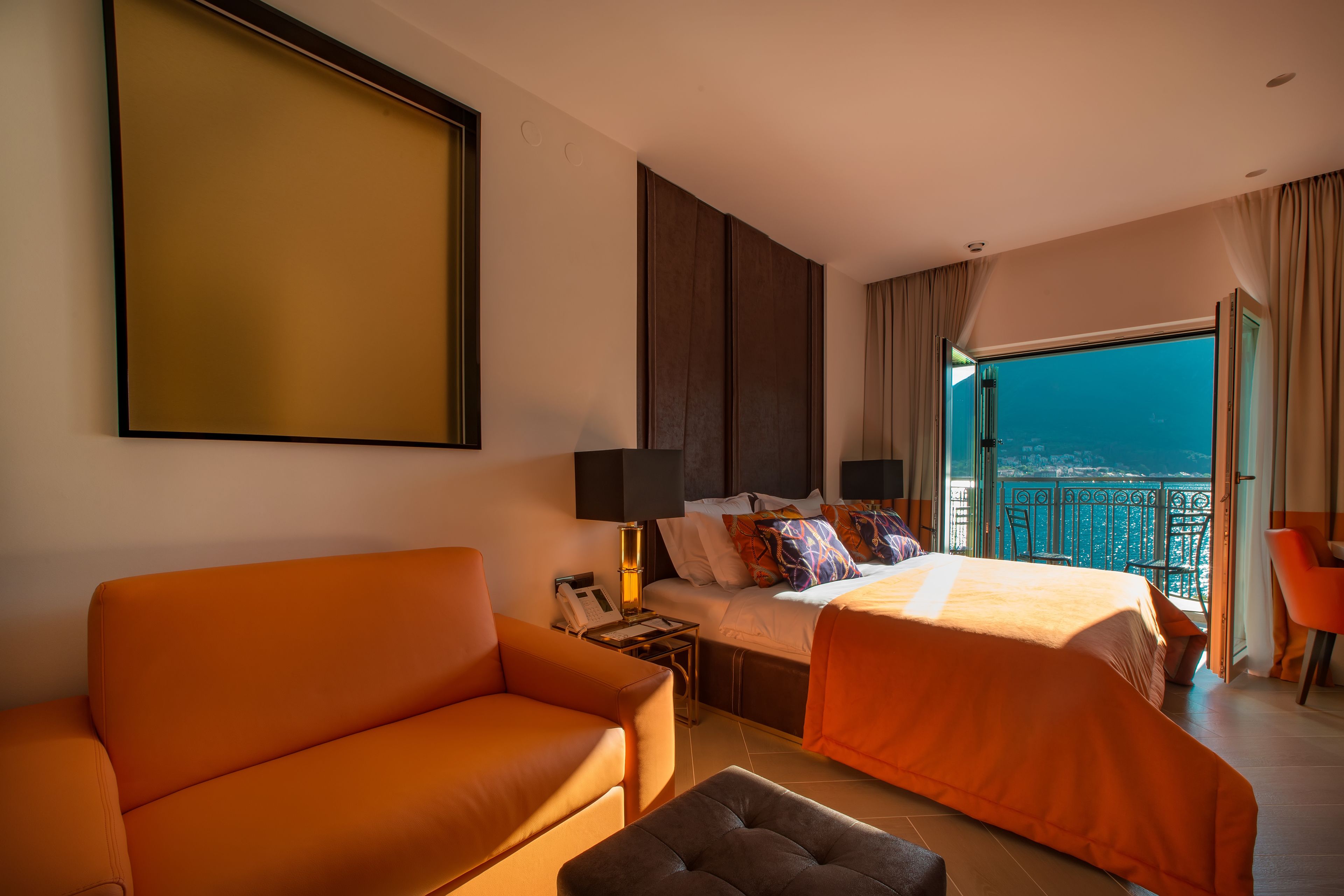 Habitación de hotel con una cama grande, un sofá y un balcón con vistas a la ciudad.