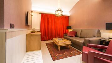 A modern living room with a sofa, red chairs, a wooden coffee table, and a patterned rug.