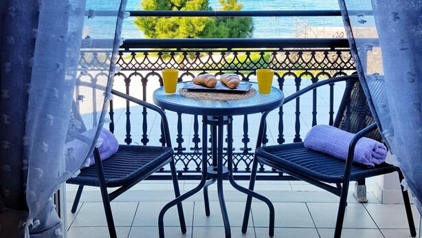 A balcony with a view of the sea, featuring a table with chairs and yellow cups. - Bel Momento (Zakynthos)