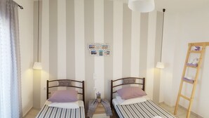 A room with two single beds, a wooden ladder, a wall-mounted photo collage, and a small table with a plant. - Bel Momento (Zakynthos)