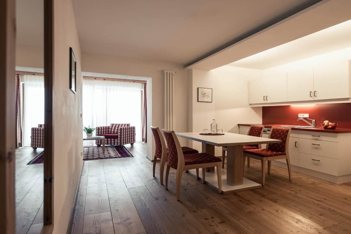 A modern kitchen with white cabinets, a wooden staircase, and a dining area with a table and chairs.