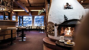 A cozy interior with a stone fireplace, wooden beams, and a bar area. - Family Resort Rainer (Sesto)