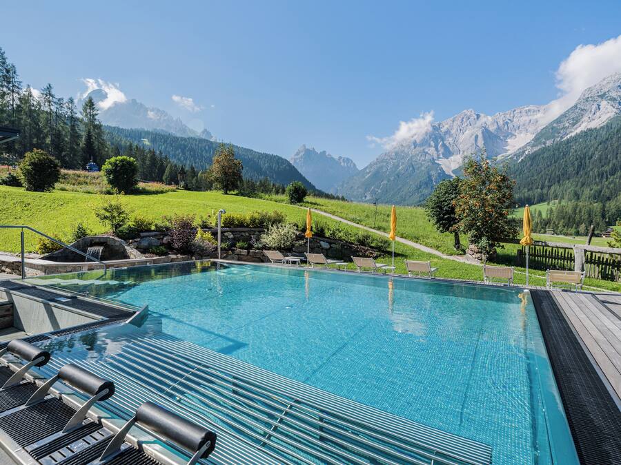 Una piscina techada, una piscina al aire libre, sombrillas