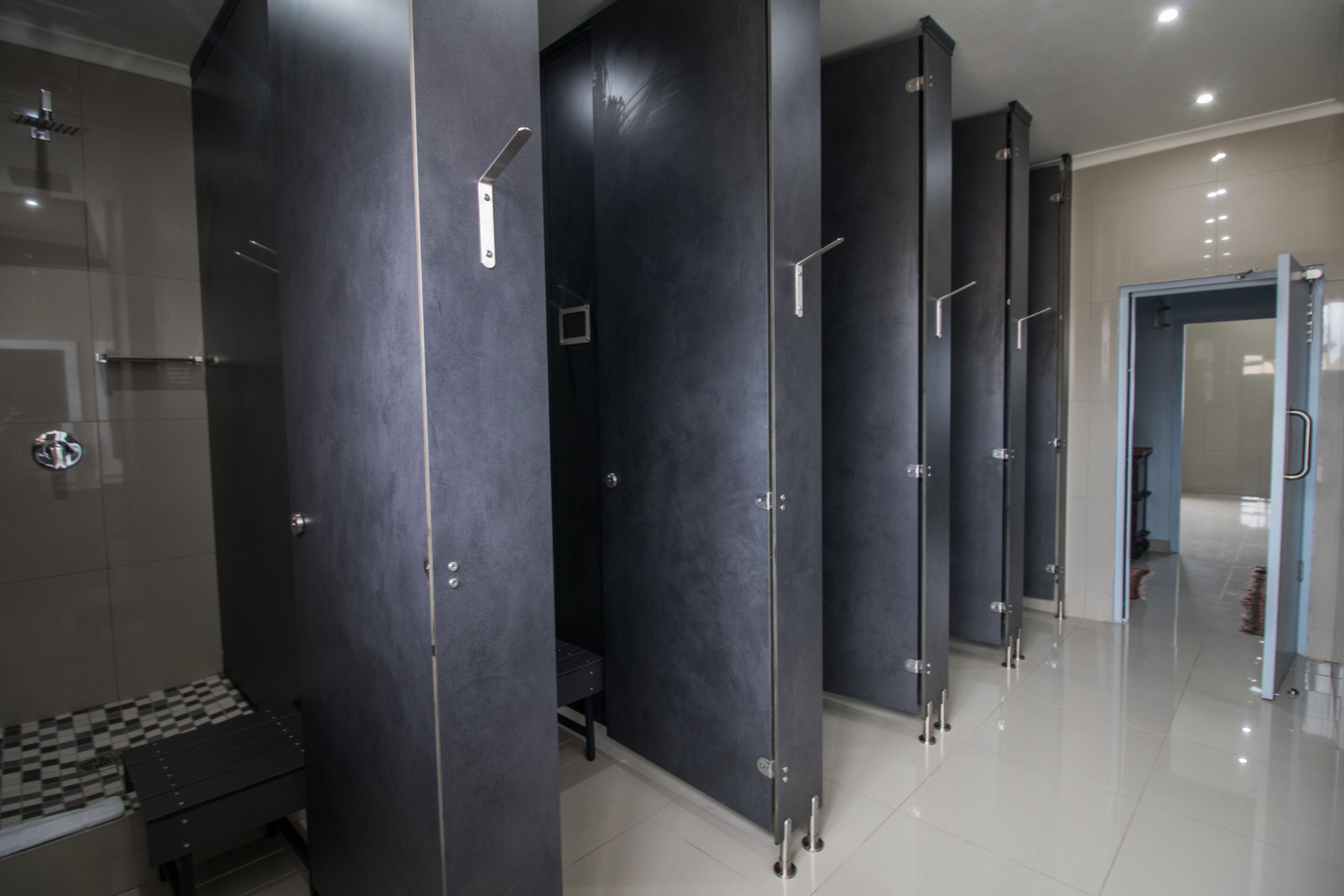 A modern bathroom with a checkered floor, dark walls, and a glass shower enclosure.