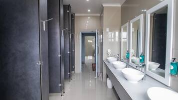 Un baño moderno con varios lavamanos, armarios oscuros y un espejo grande.