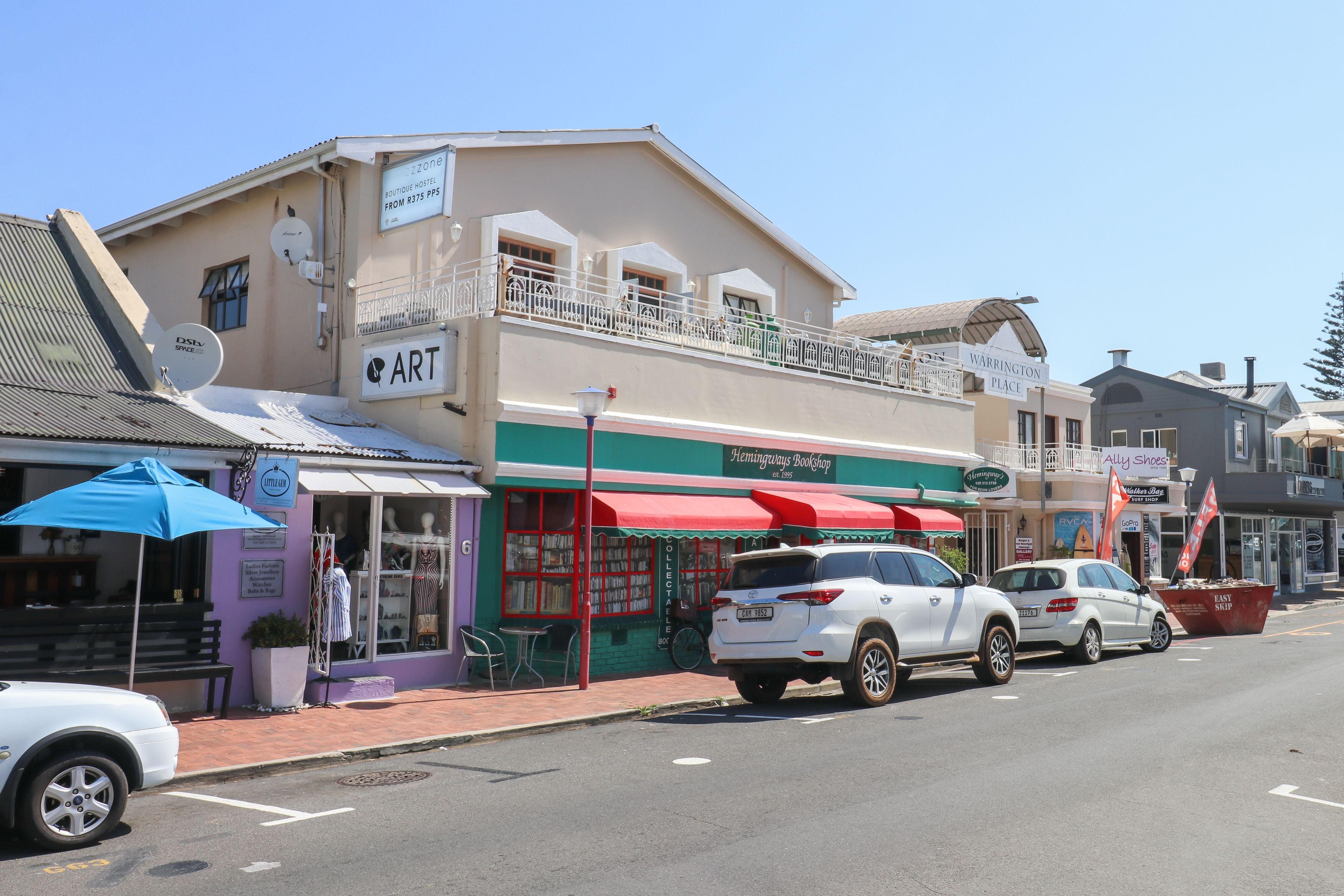 A two-story building with a balcony, a storefront with a red awning, and a sign for 'Warrington Place'.