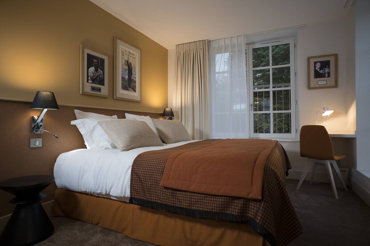 Een hotelkamer met een bed, twee bedlampen, een bureau en een stoel.