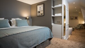 Moderni hotellihuone, jossa on suuri sänky, vaatekaappi ja oleskelualue.