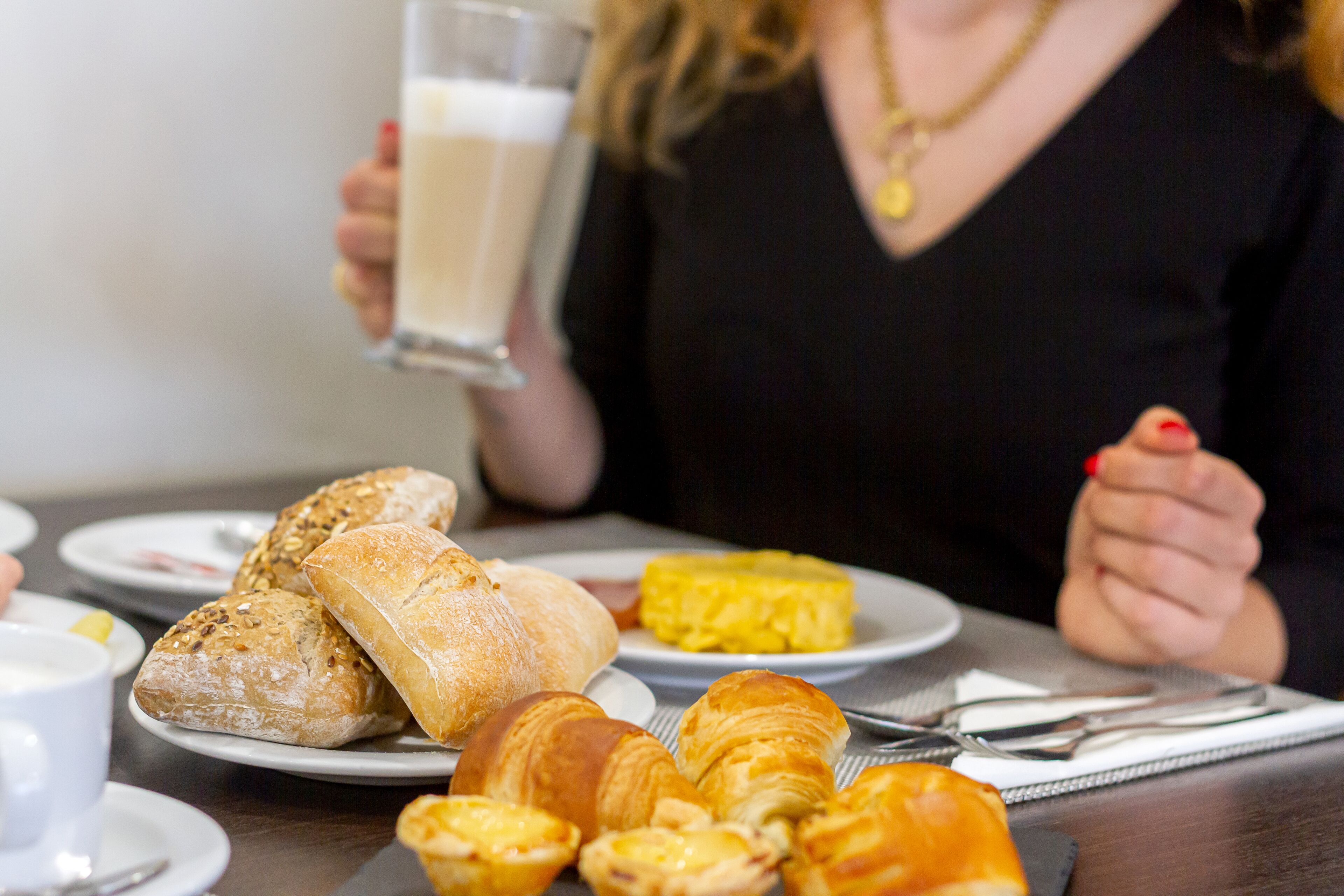 A dining table with croissants, a glass of milk, and a plate of scrambled eggs.