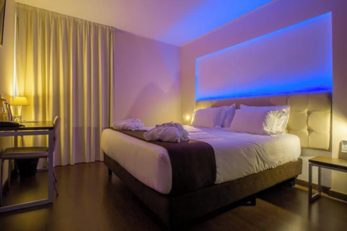 A hotel room with a bed, a desk, and a chair.