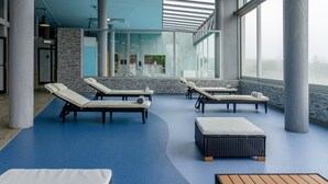 A modern indoor pool area with lounge chairs and a seating area. - In Gold Hotel & Spa (Agueda)
