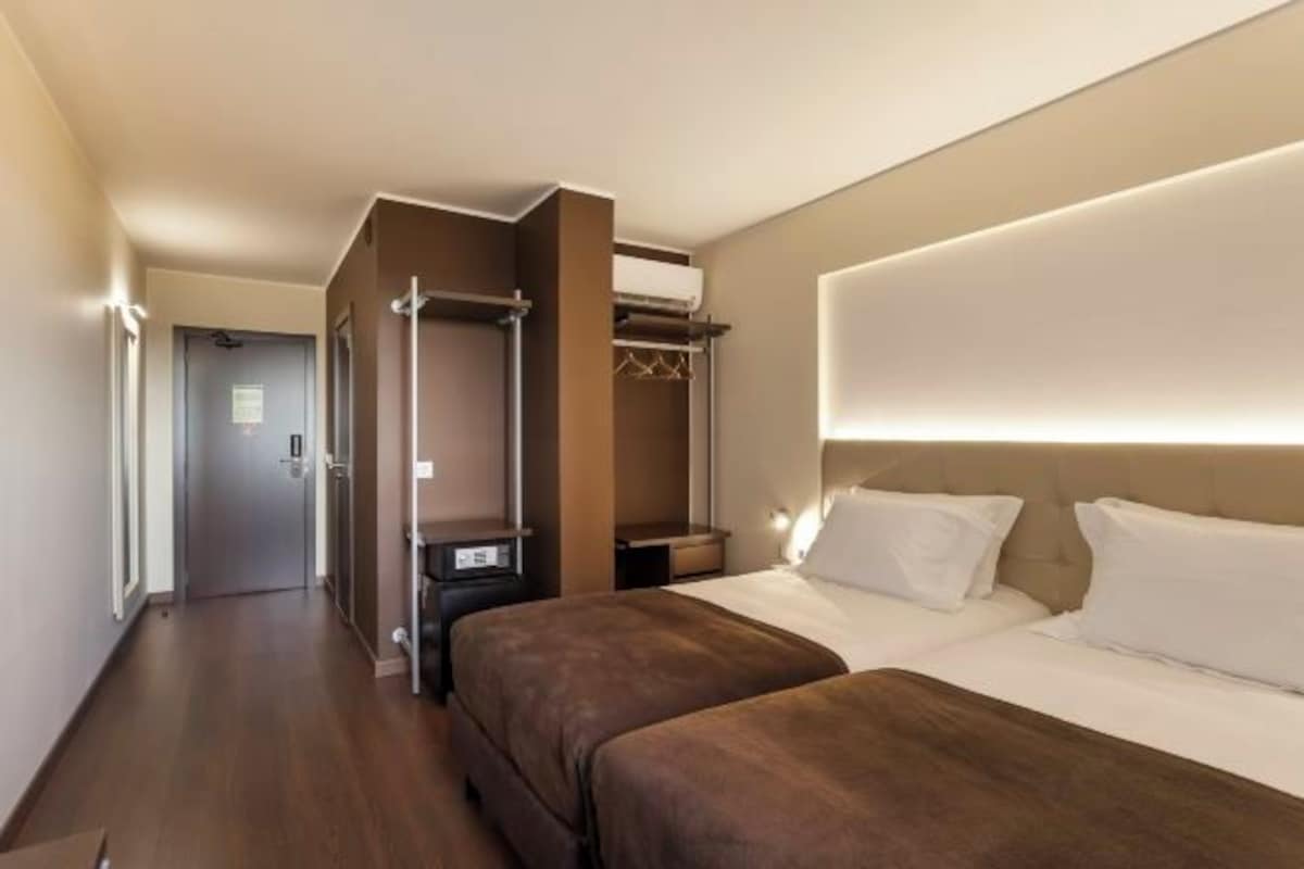 A hotel room with a bed, bedside tables, a wardrobe, and a walk-in closet.