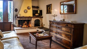 A cozy living room with a fireplace, a sofa, a coffee table with wine glasses, and a dresser. - Villa Nuba,Perugino villa-apt.5min to downtown,playground,Eco pool,barbecue,wifi (Perugia)