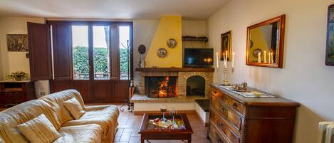 A living room with a sofa, coffee table, fireplace, and a television.