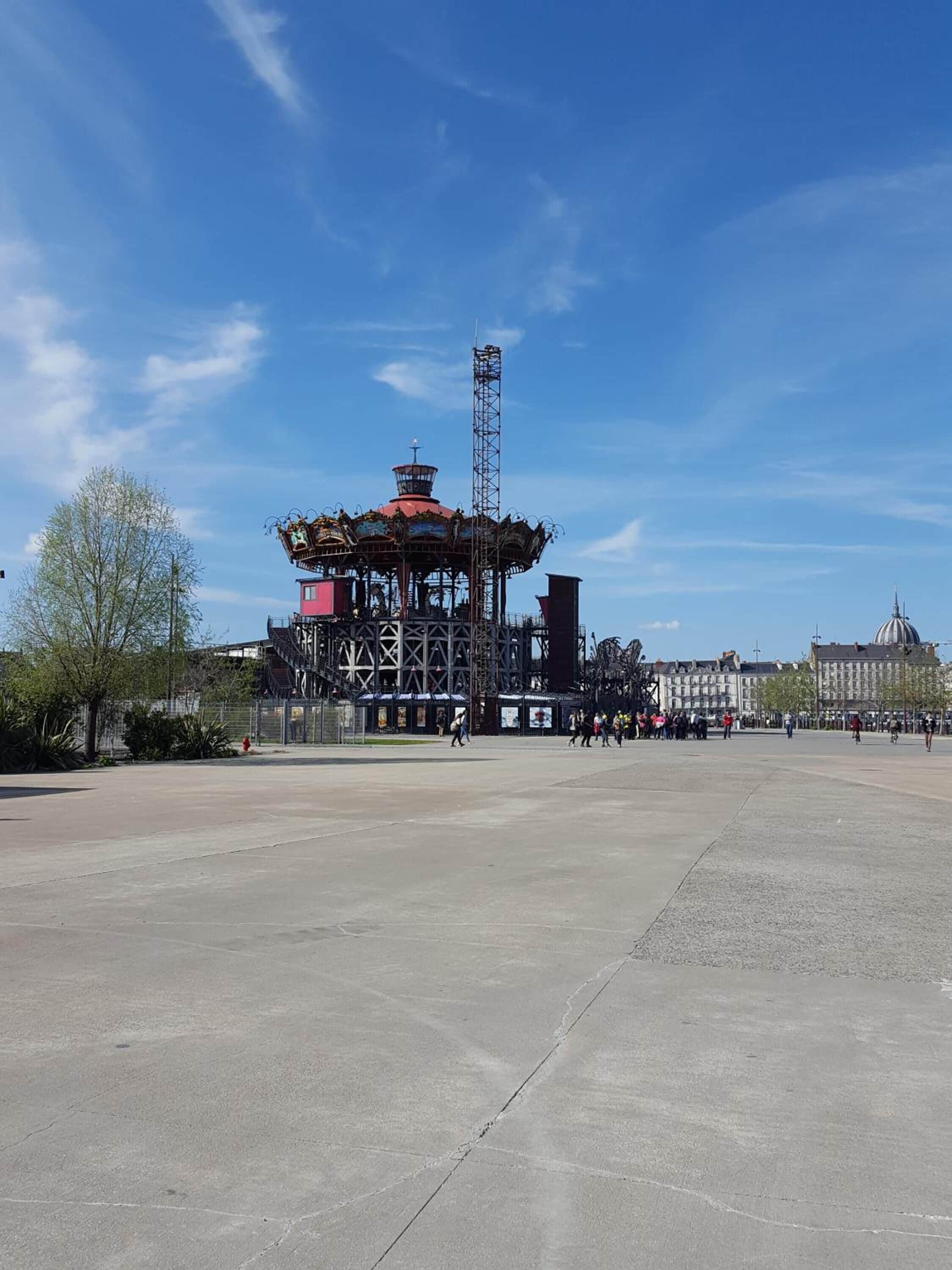 A large open plaza with a carousel and a tall tower structure.