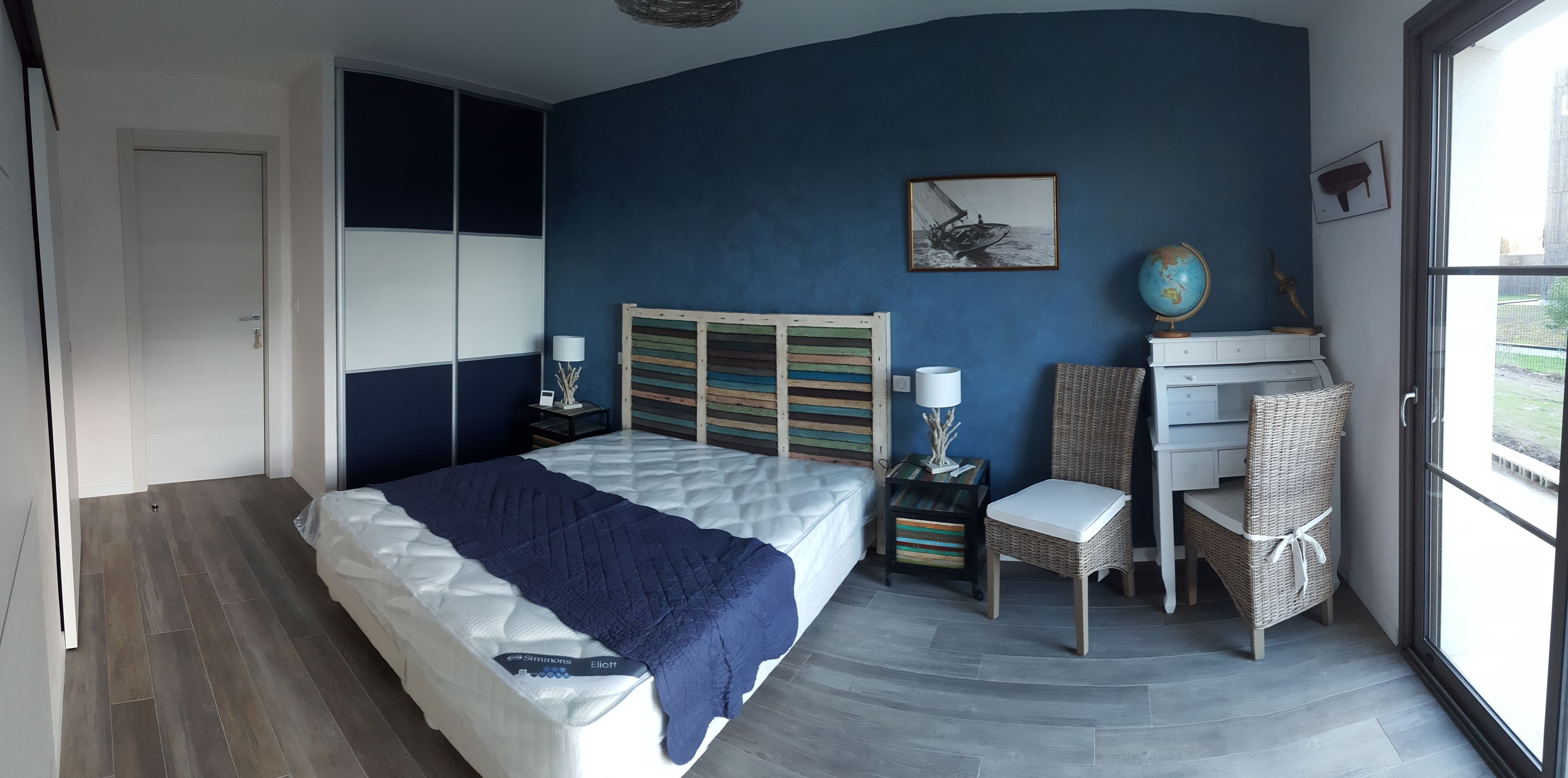 A bedroom with a bed, a desk, a chair, a globe, and a picture on the wall.