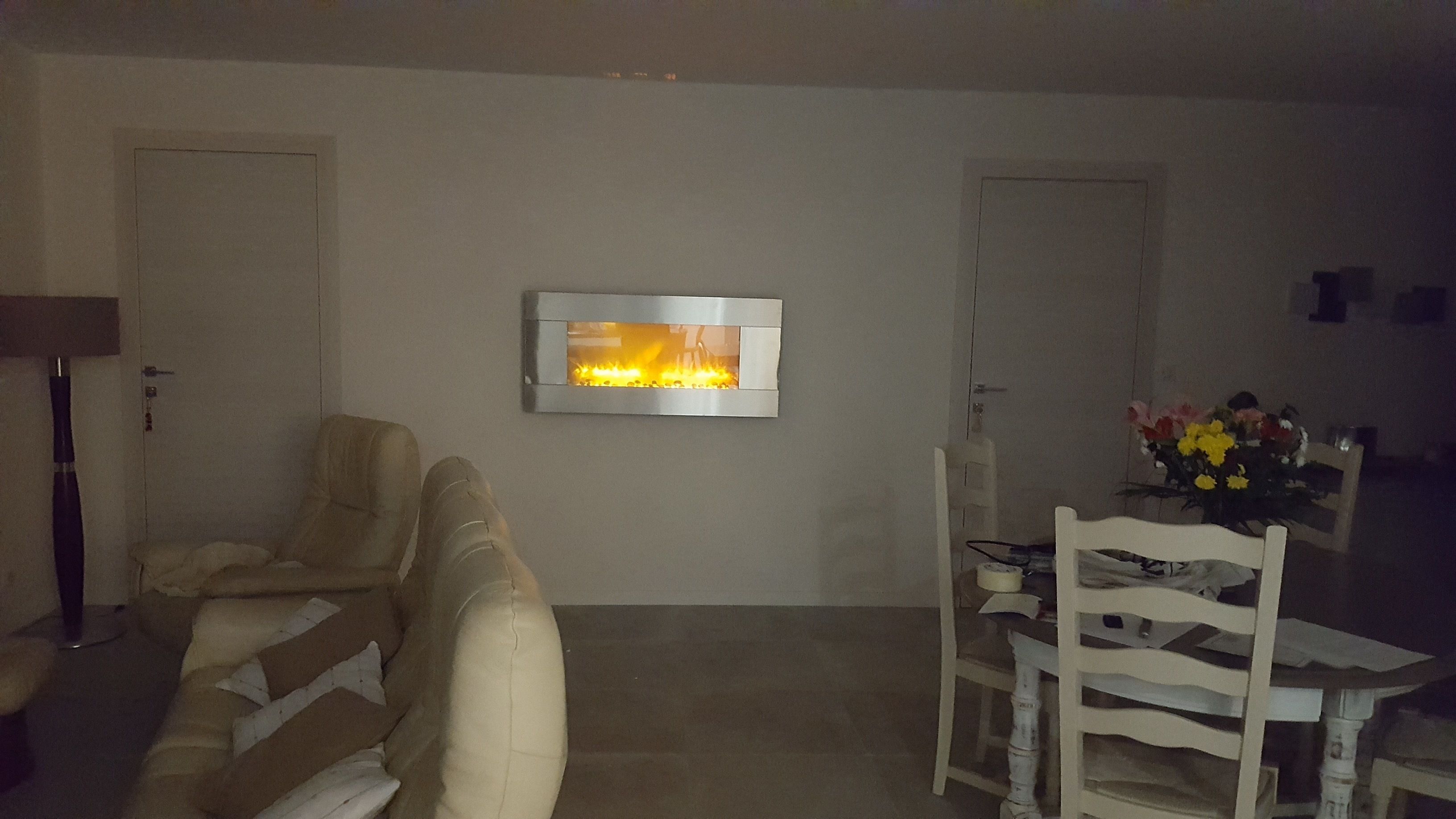 Un saló amb una llar de foc, un sofà, una taula de menjador amb cadires i un ram de flors.