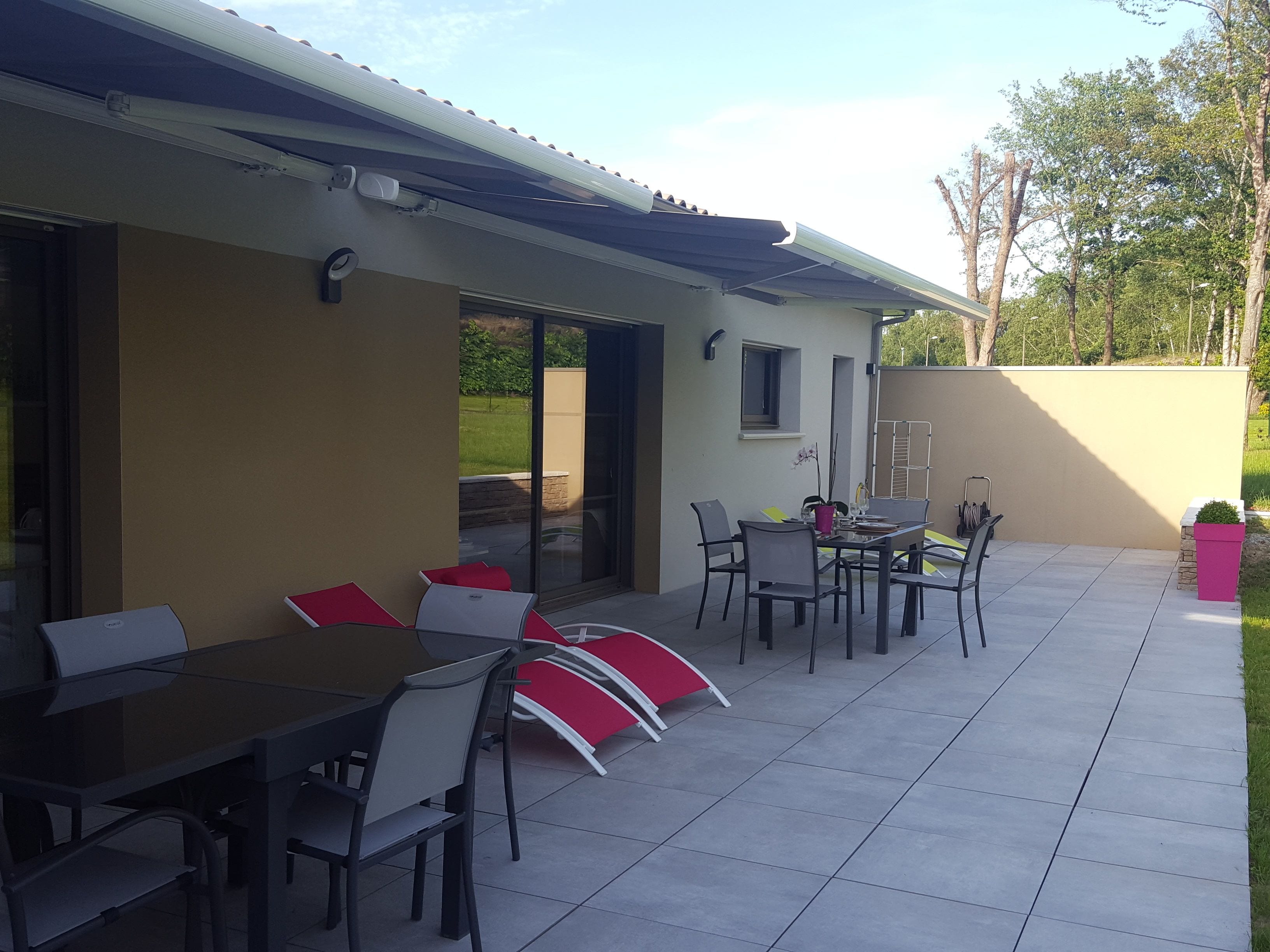 Un espace extérieur aménagé en terrasse, avec une table et des chaises, un barbecue et une plante en pot.