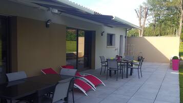 Un espace extérieur aménagé en terrasse, avec une table et des chaises, un barbecue et une plante en pot.