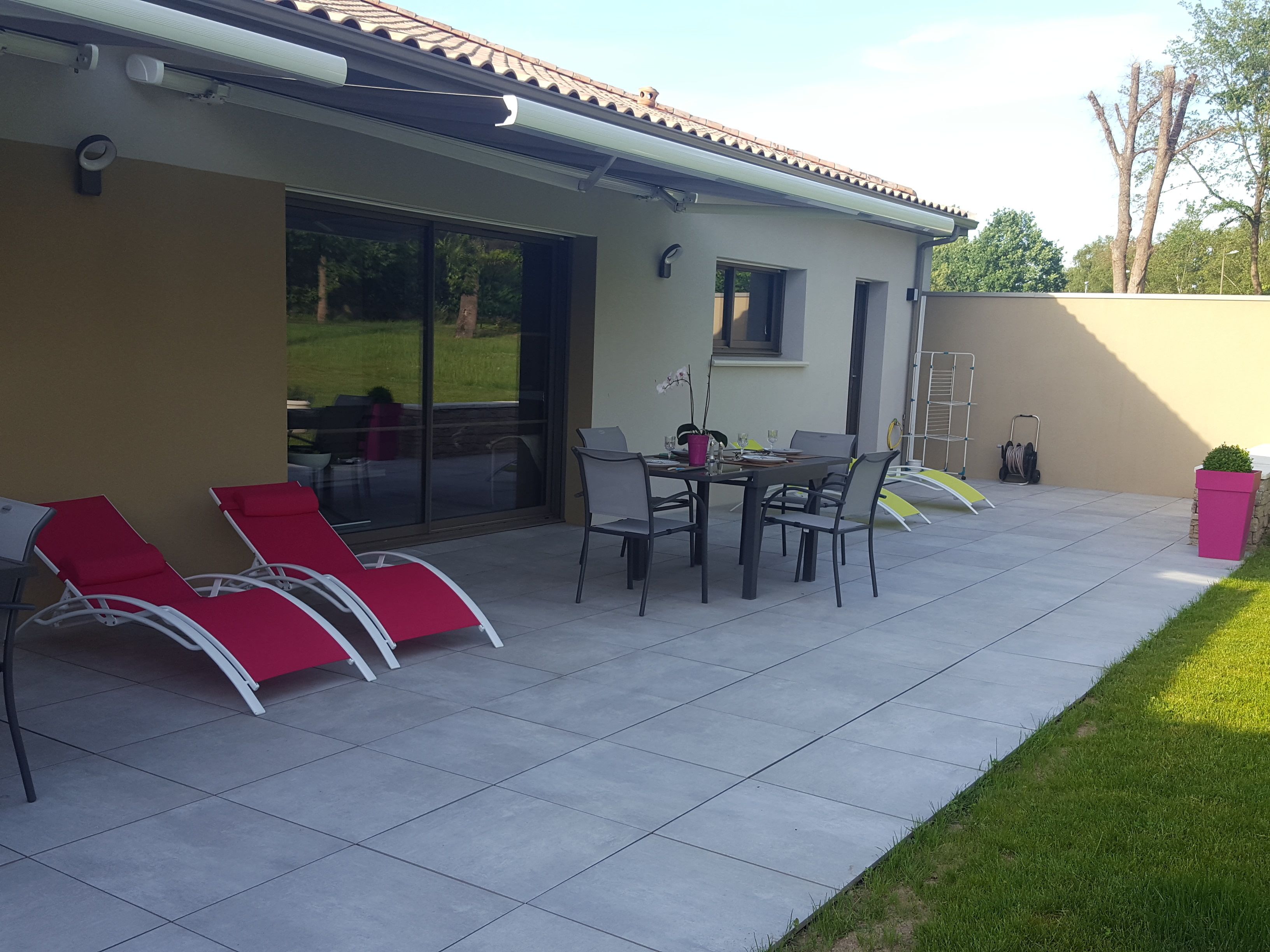 A patio with a table and chairs, a sliding glass door, and a small garden area with a pink planter.