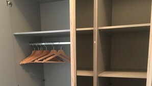 Een inloopkast met houten deuren, een kledingroede en verschillende planken.