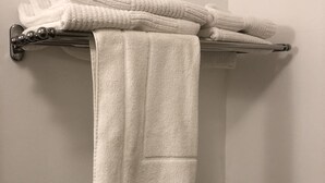 Een badkamer met een handdoekhouder, gevuld met opgevouwen handdoeken en een loshangende handdoek.