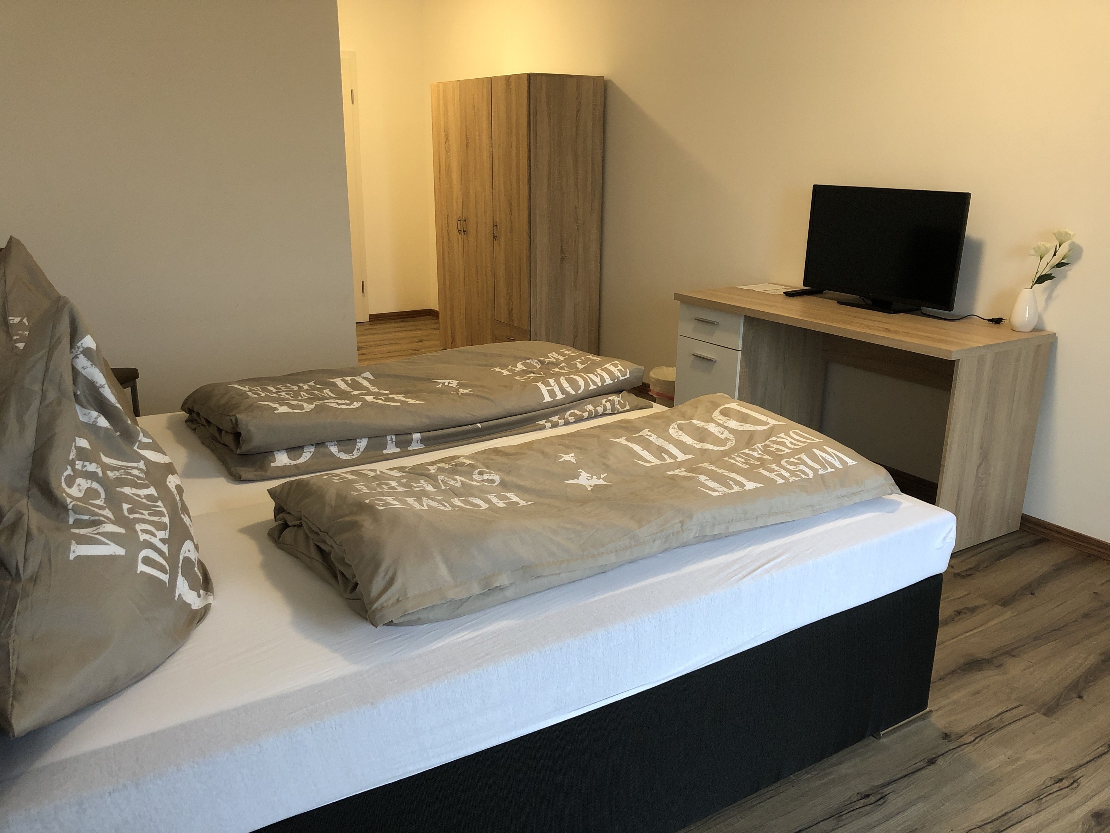 Un dormitorio con cama, almohadas, televisor y escritorio.