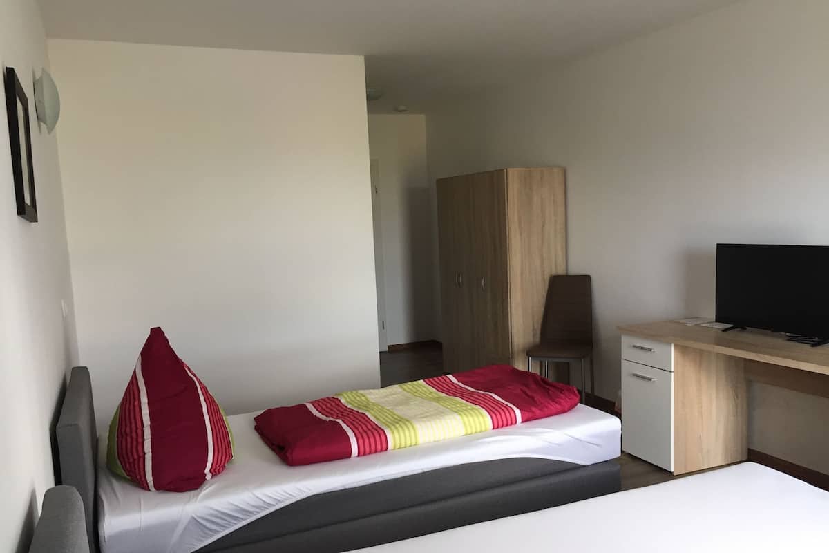 A hotel room with a bed, a desk, a television, and a wardrobe.