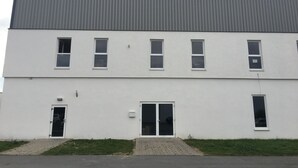 Een gebouw met twee verdiepingen, een plat dak, meerdere ramen en een deur.