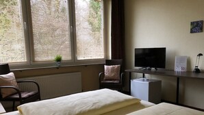 Quarto de hotel com duas camas, televisão, escrivaninha e uma cadeira.