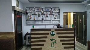 A hotel reception area with a wooden reception desk, a wall-mounted liquor shelf, and a 'No Admission' sign on the door. - Tropical Suites (Phuntsholing)