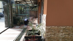A building with a stone facade, a covered outdoor seating area, and potted plants. - Tropical Suites (Phuntsholing)