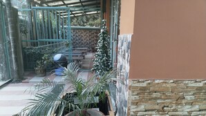 A patio area with potted plants, a stone wall, and a covered seating area. - Tropical Suites (Phuntsholing)