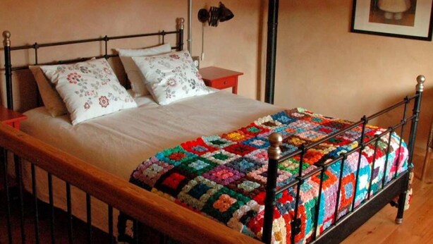 Ein Bett mit einer farbenfrohen Steude, einem Holzkopfschild und einem Nachttisch mit einer Lampe.
