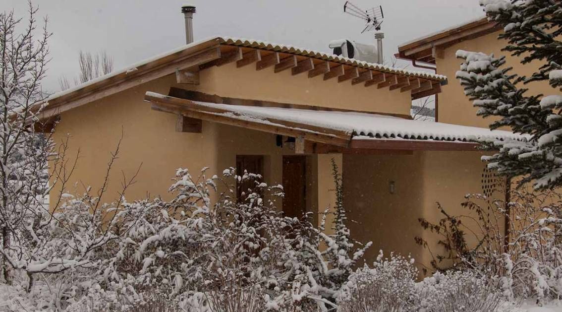 Un edificio de dos plantas con tejado inclinado, una chimenea y una antena parabólica.