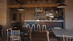 Ein Restaurant mit Barbereich, Holzbalkendecke und Barhocker.