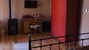 Ein Zimmer mit einem Holztisch, einem roten Kleiderschrank, einem Stuhl, einem Fernseher und einem Kamin.
