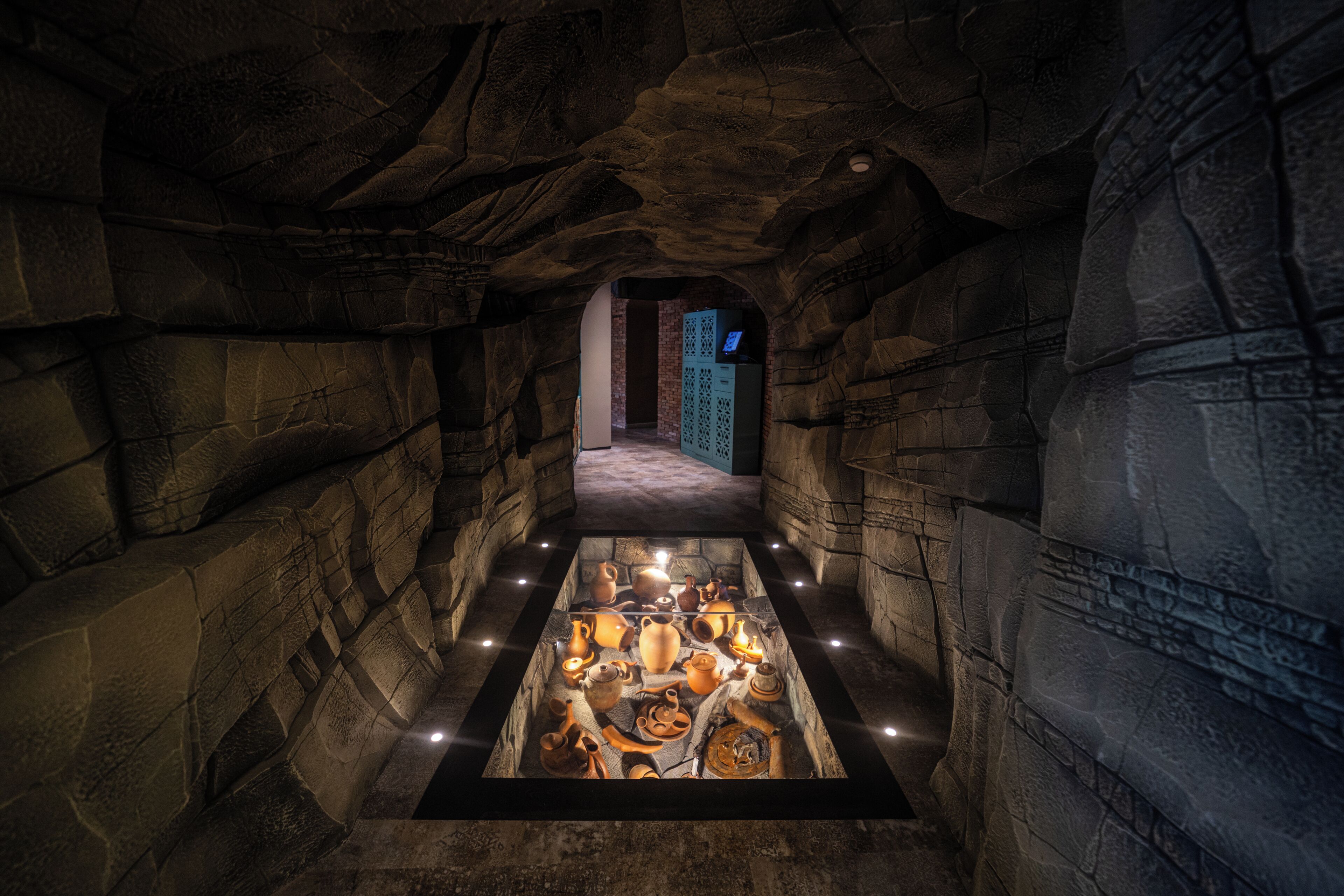 Un pasillo de paredes de piedra con una exhibición central de cerámica y artefactos.