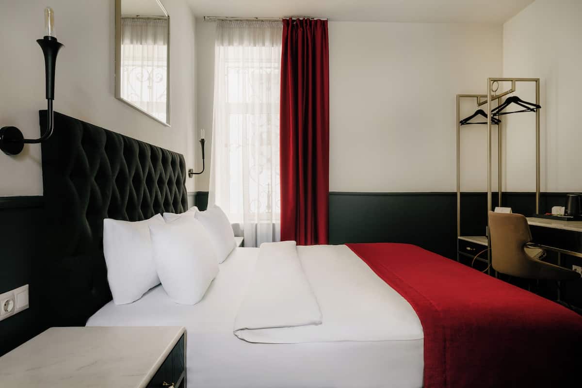 Habitació d'hotel amb un llit, escriptori, cadira, penjador i mirall.