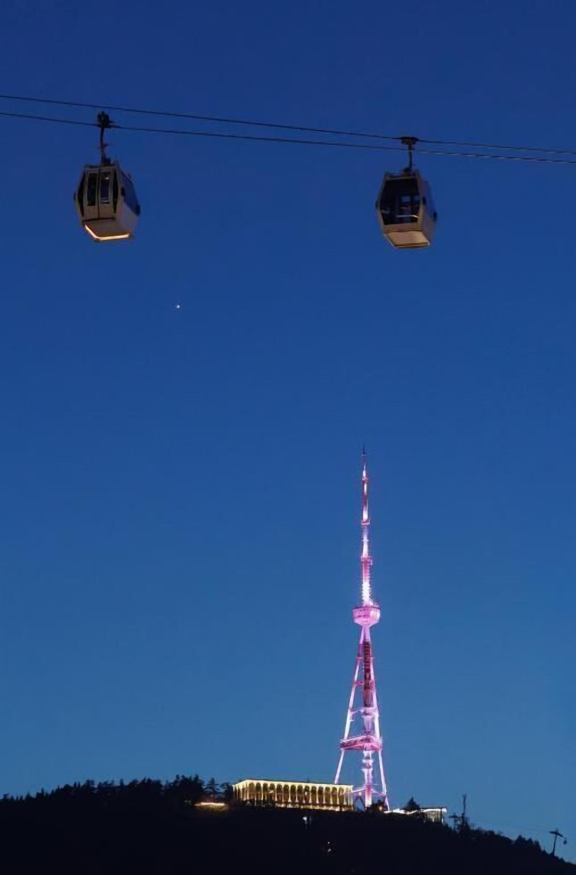 A cable car system with a lit tower in the background.