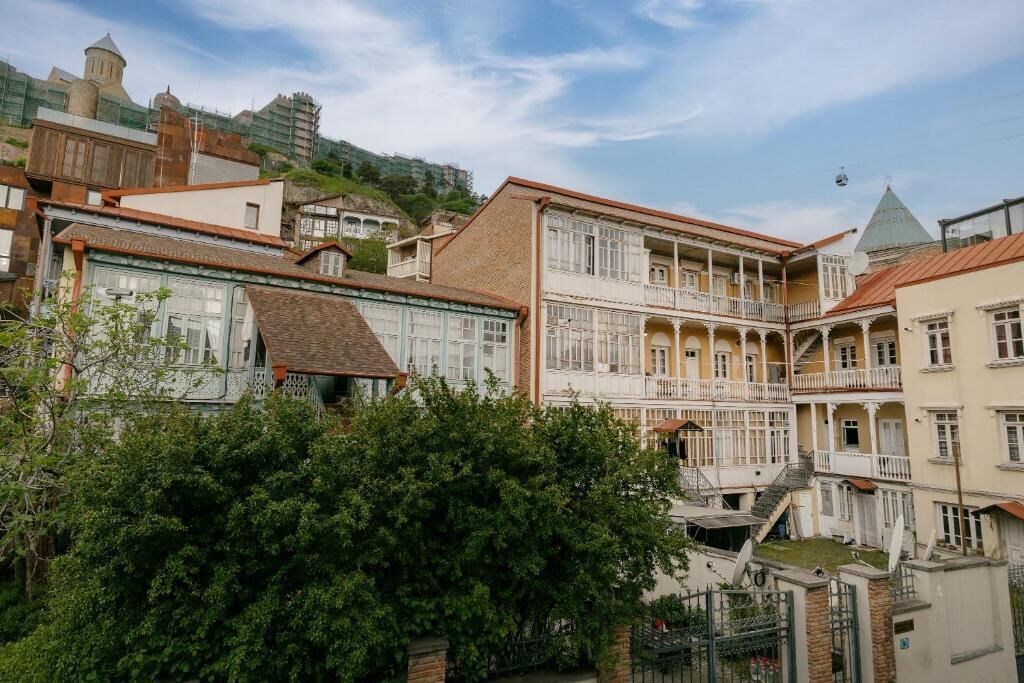 Un immeuble à plusieurs étages doté de balcons, d’une cour intérieure et d’une colline en arrière-plan.
