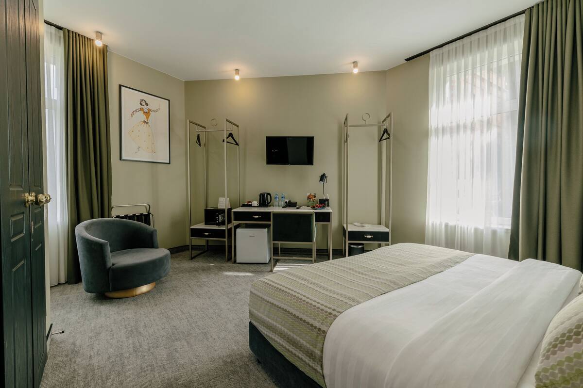Habitació d'hotel amb llit, escriptori, cadira, televisió i armari.