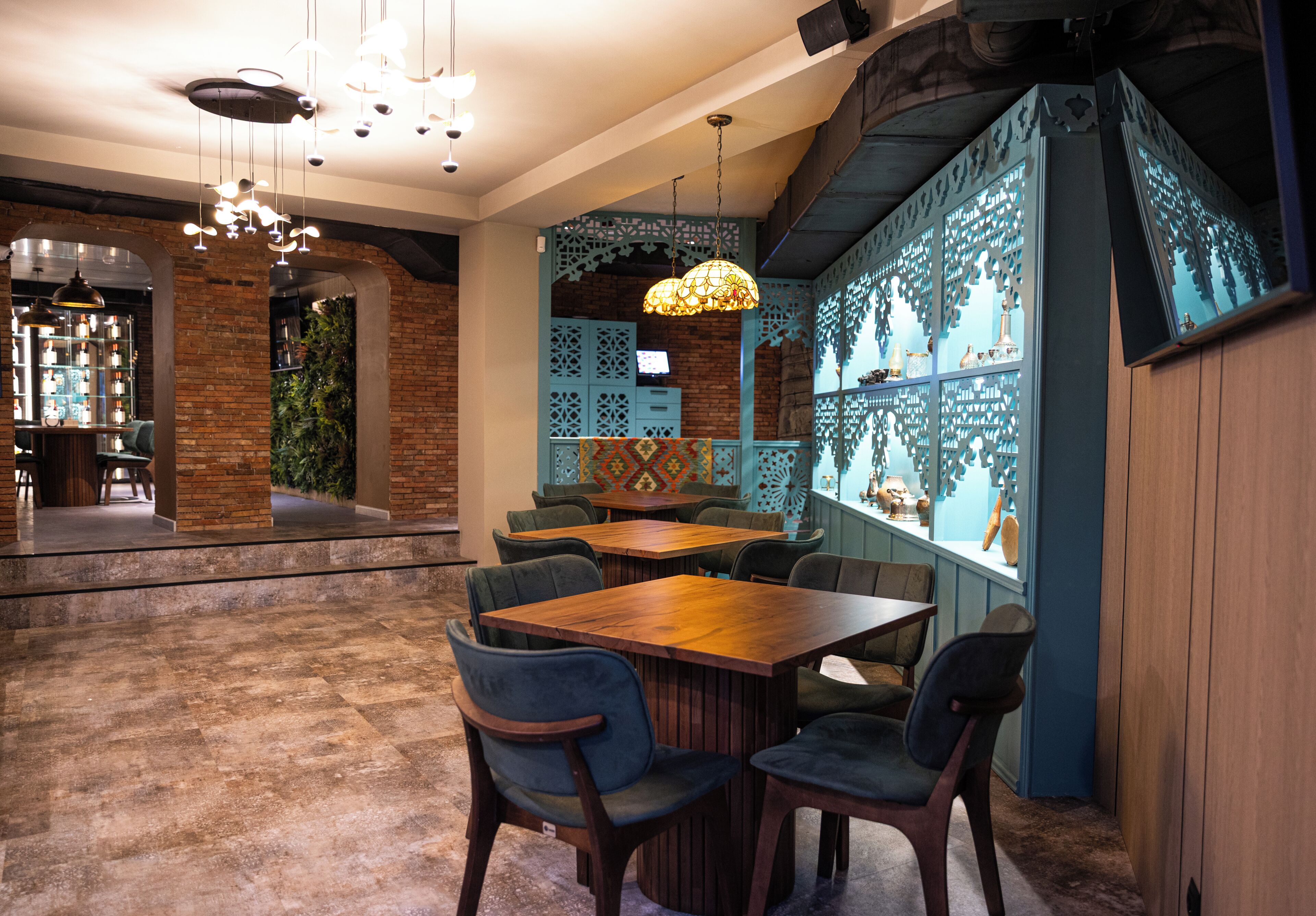 Interior de restaurant amb parets de maó, taules de fusta i cadires blaves.