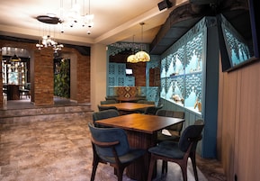 Un interior de restaurante con paredes de ladrillo, mesas de madera y sillas azules.