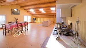 A spacious dining area with wooden beams, a kitchen with a stove and utensils, and a cozy living space with a sofa and a television. - Agriturismo da Rosi - villa with pool, Casa Sofia (codevigo)