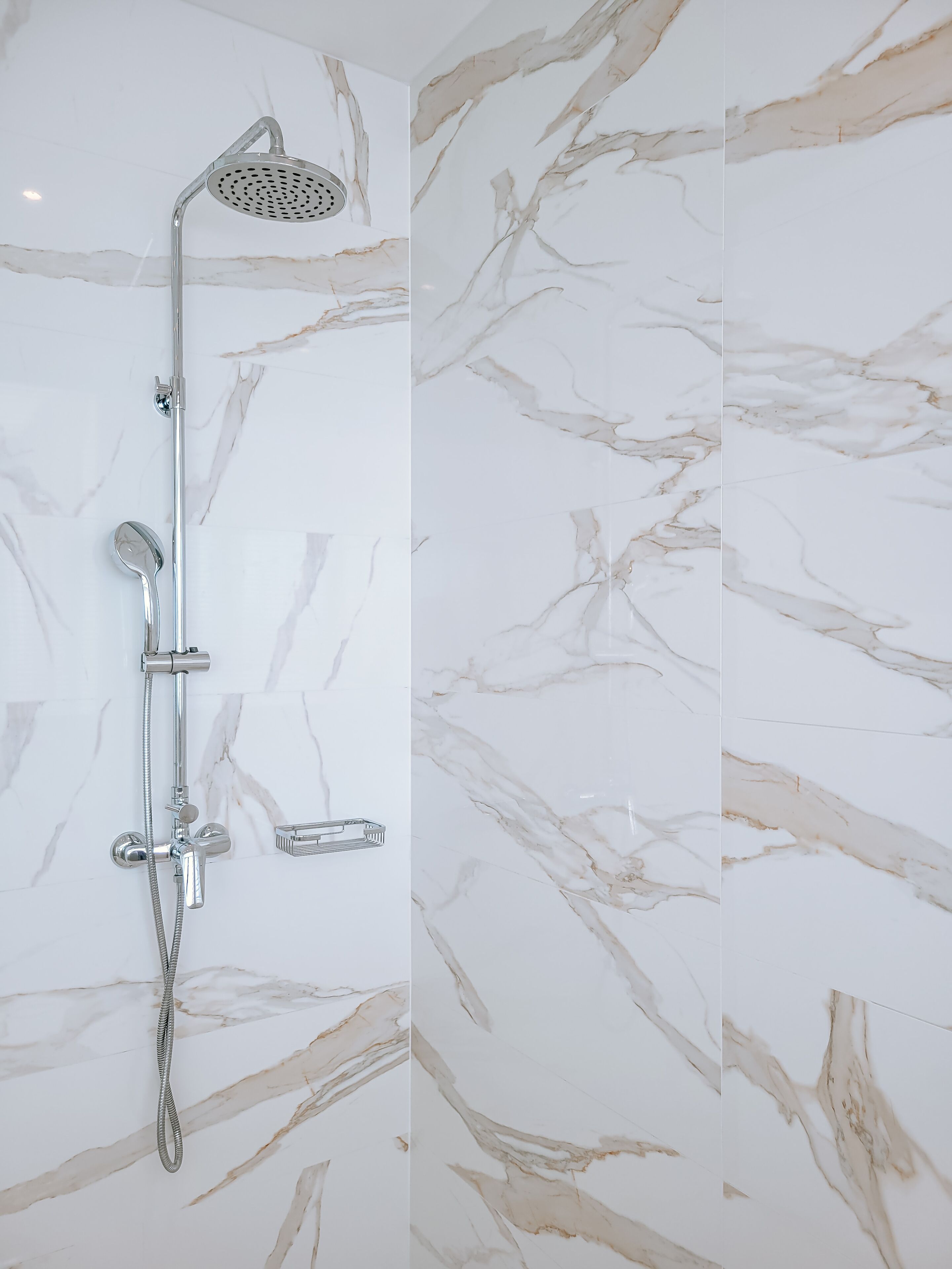 Un baño moderno con ducha, cabezal de ducha manual y masajeador manual.
